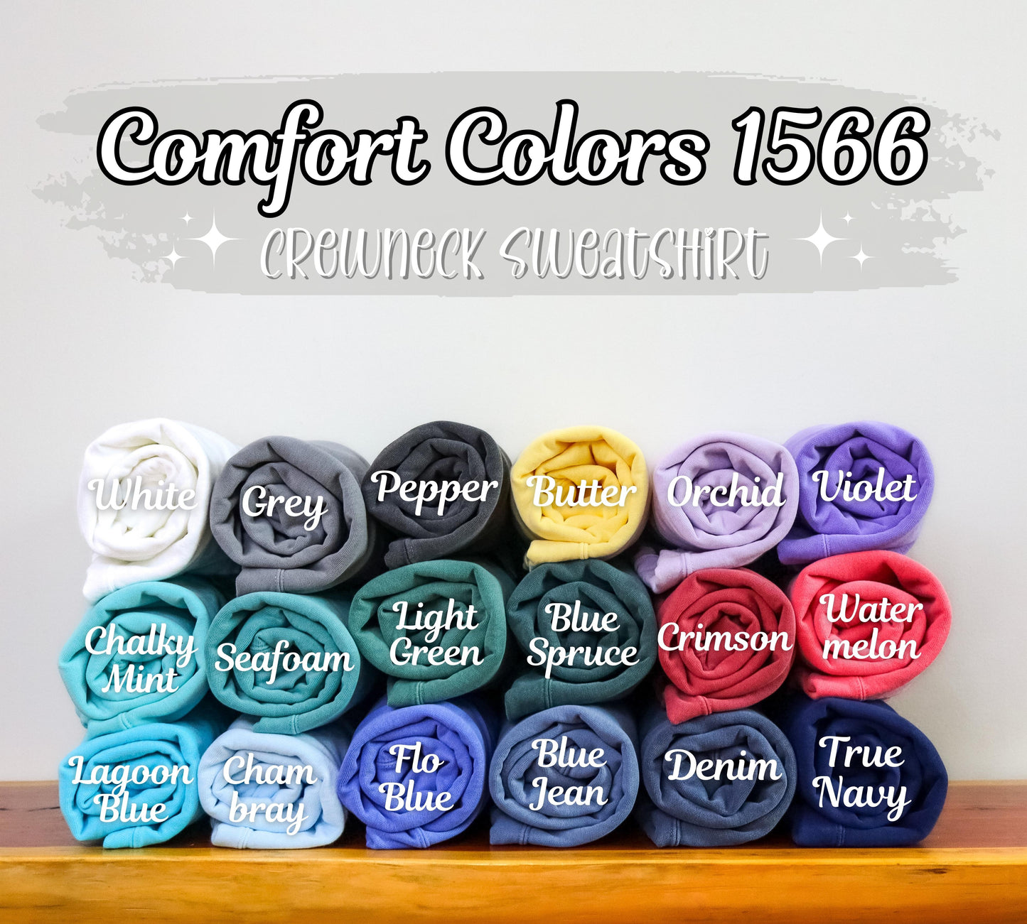 Collection of folded sweatshirts in various colors with labels on a wooden surface.