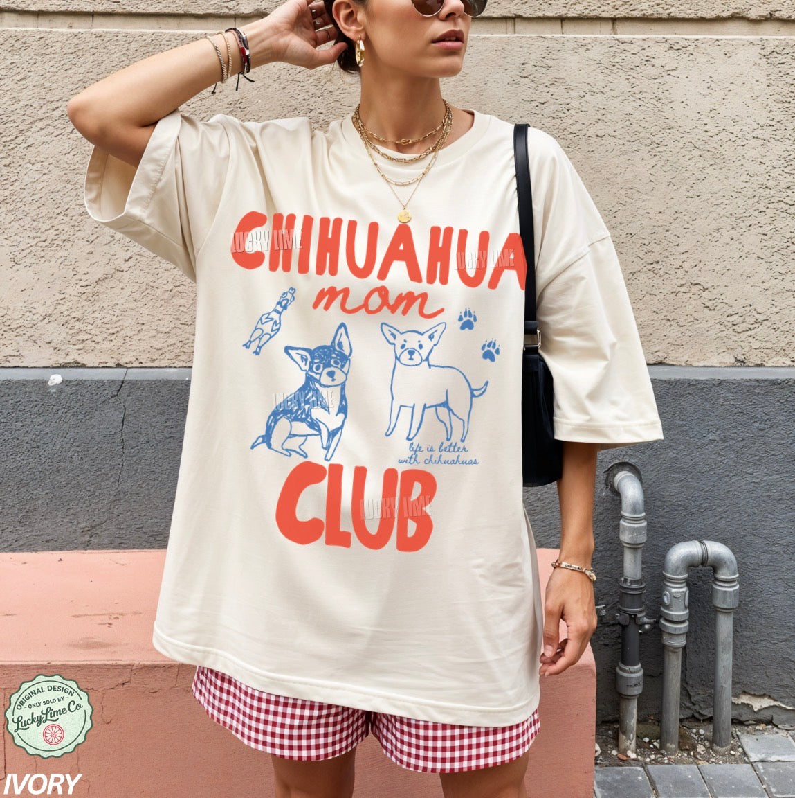 Person wearing a t-shirt with 'Chihuahua mom club' design against a wall.
