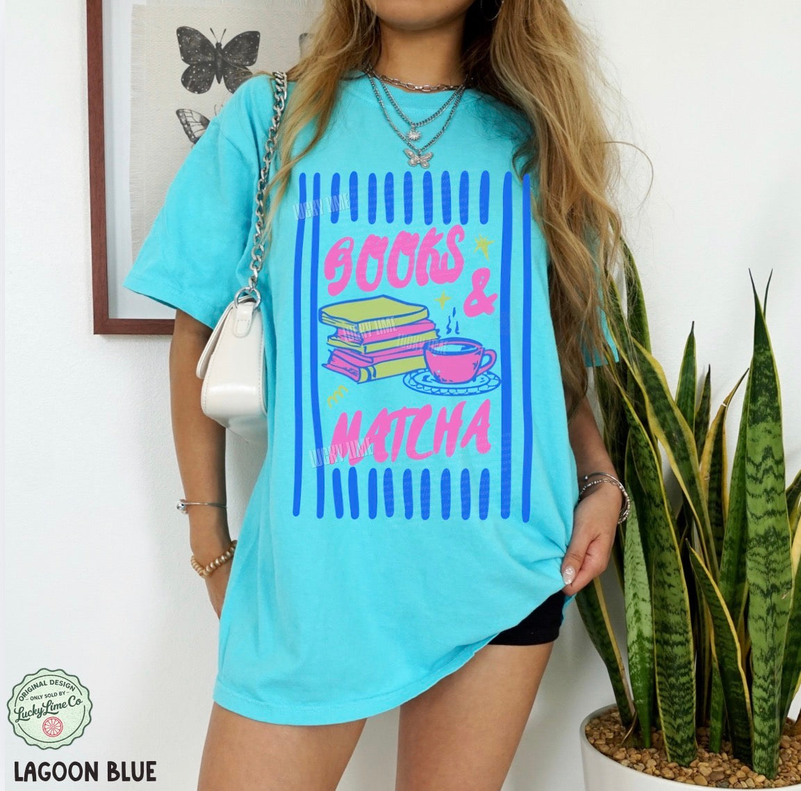 Person wearing a light blue t-shirt with 'Books & Matcha' design, standing next to a plant.