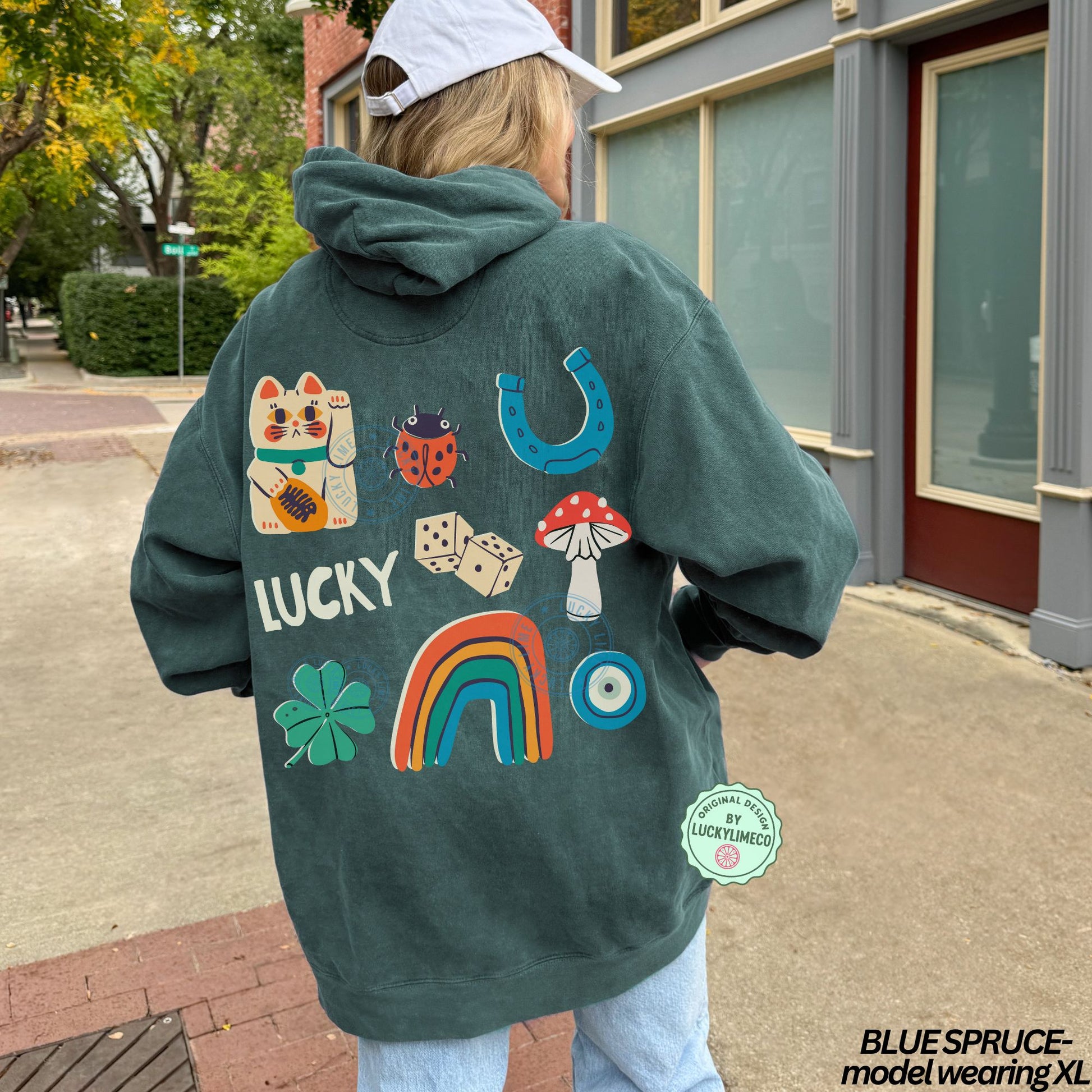 Person wearing a green hoodie with lucky symbols on the back, standing on a sidewalk.