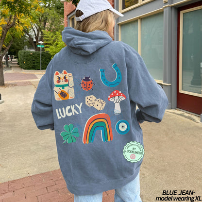 Person wearing a blue hoodie with colorful lucky icon designs and text, standing on a sidewalk.