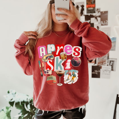 Person wearing a red sweatshirt with 'Apres Ski' design, taking a mirror selfie.