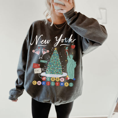 Person wearing a gray sweatshirt with Christmas-themed graphics and text.
