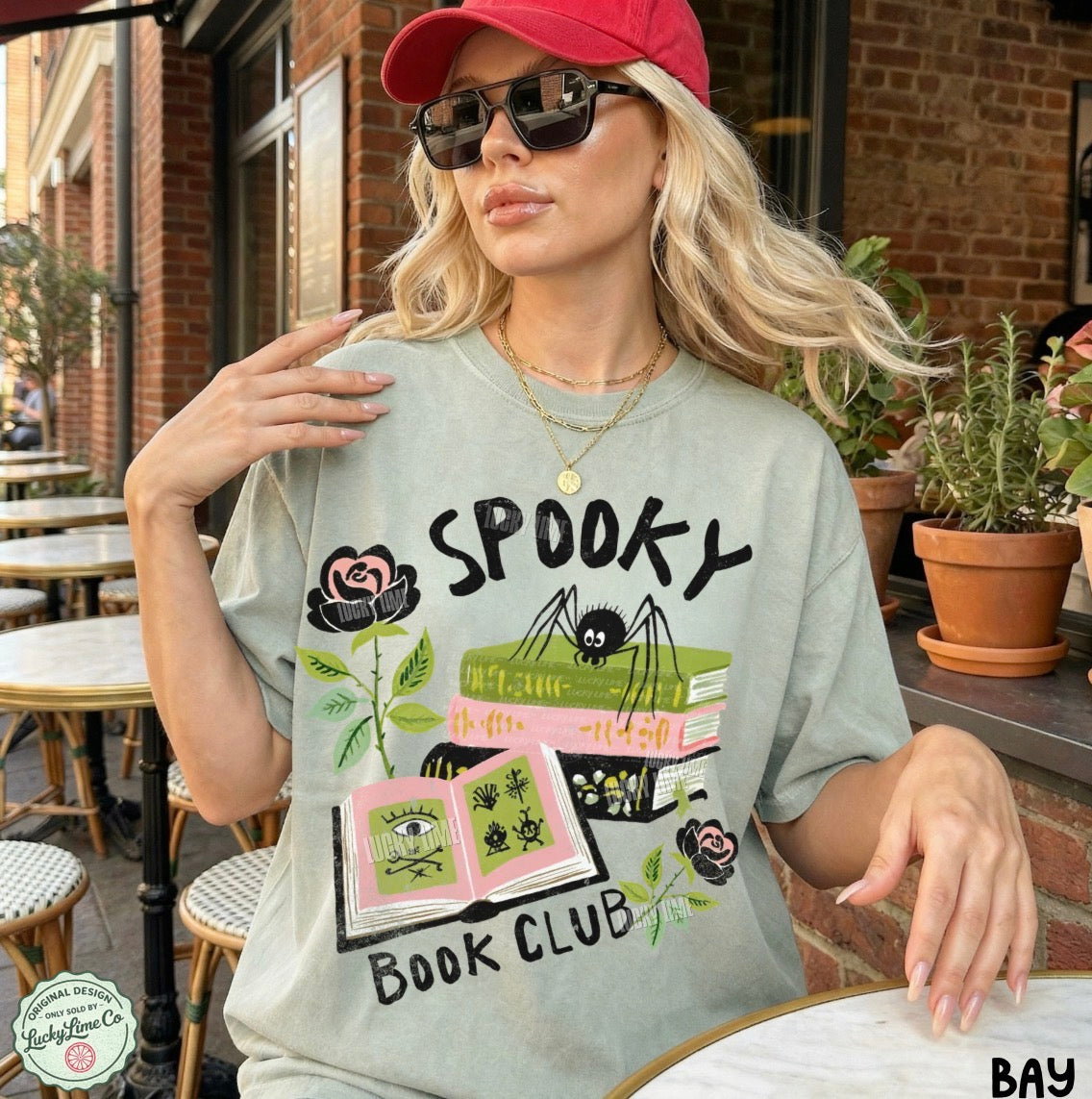 Woman wearing a 'Spooky Book Club' t-shirt outdoors.