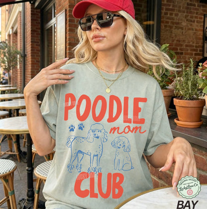 Woman wearing a t-shirt with 'Poodle Mom Club' design outdoors.