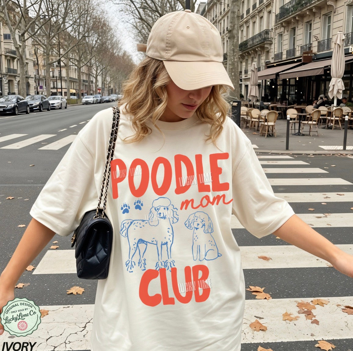 Person wearing a 'Poodle Mom Club' t-shirt on a city street.