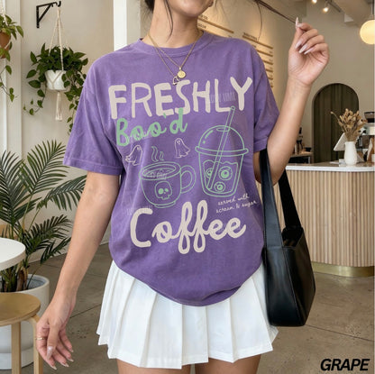 Person wearing a purple t-shirt with 'Freshly Brewed Coffee' text and graphics in a casual setting.