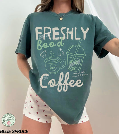 Person wearing a teal t-shirt with 'Freshly Bood Coffee' text and graphics on a white background