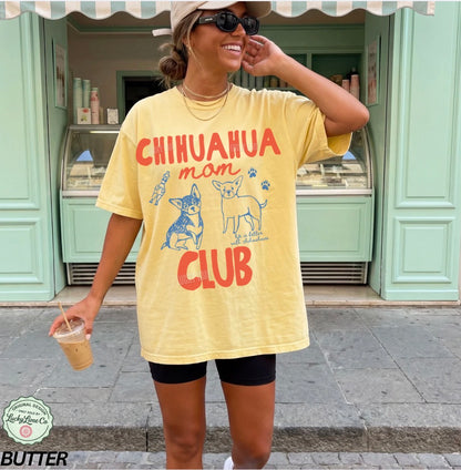 Woman wearing a yellow 'Chihuahua Mom Club' t-shirt in front of a store.