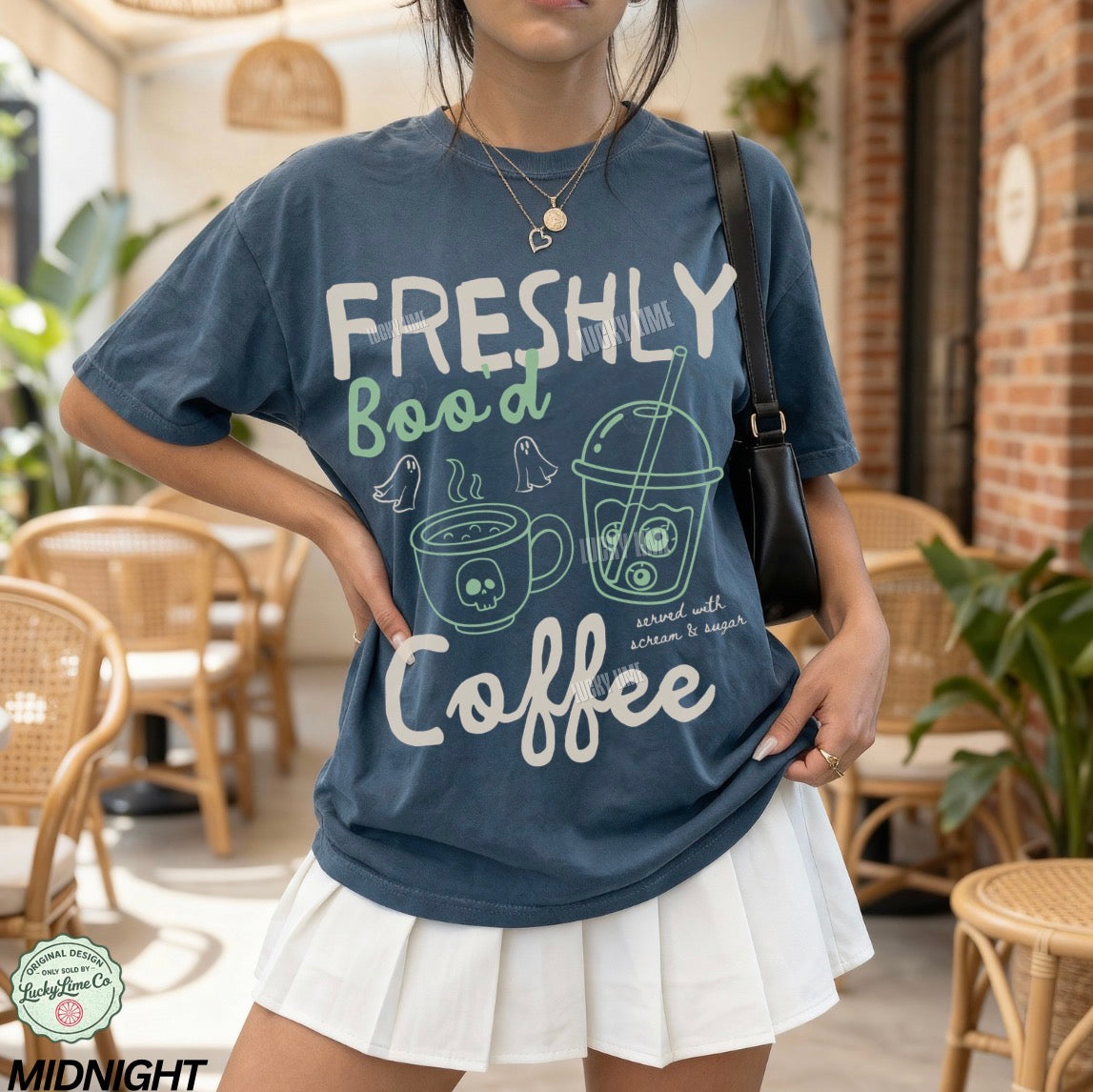 Person wearing a blue t-shirt with 'Freshly Bood Coffee' text and graphics in a casual setting.