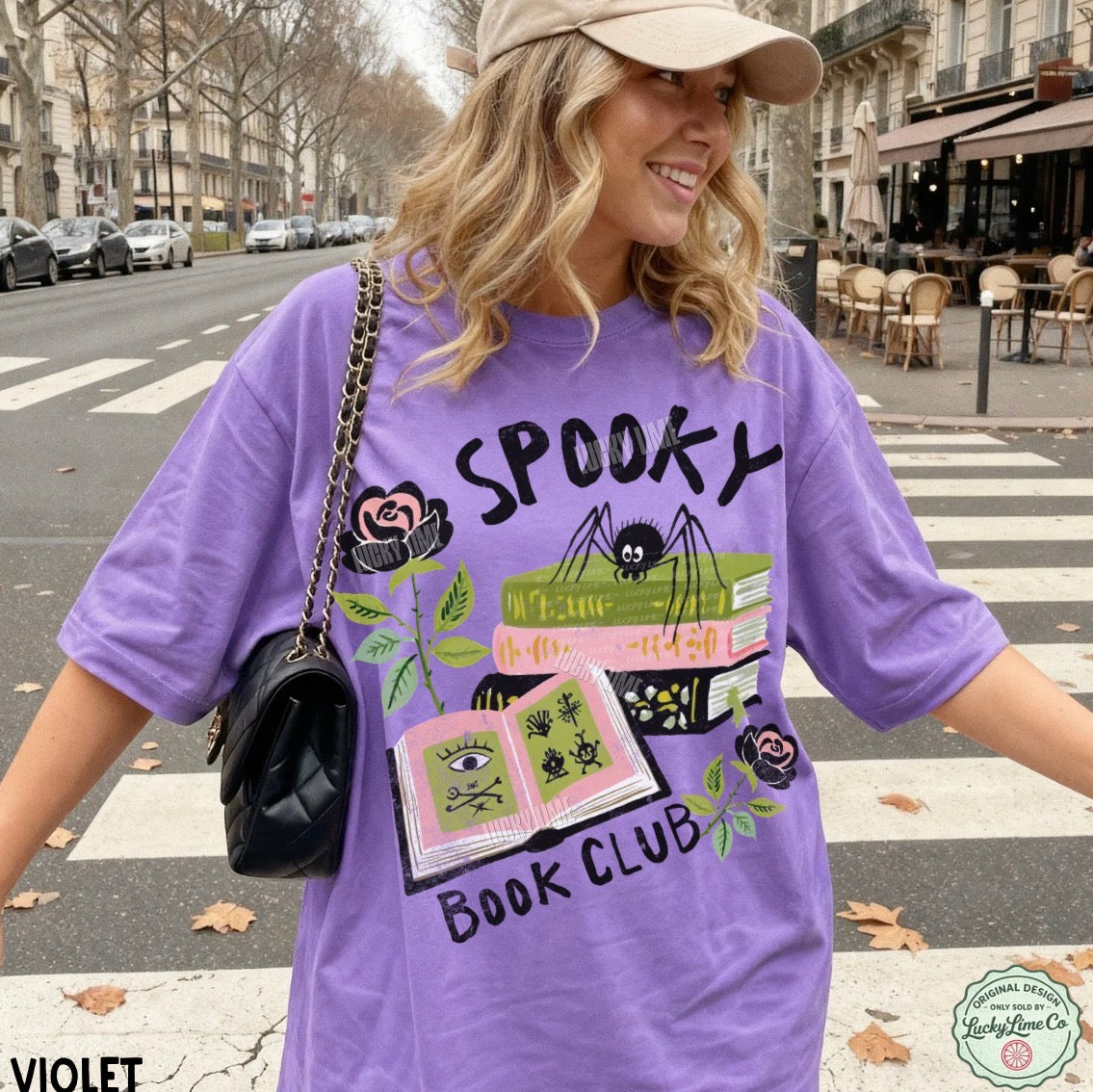 Woman wearing a purple 'Spooky Book Club' t-shirt on a city street.