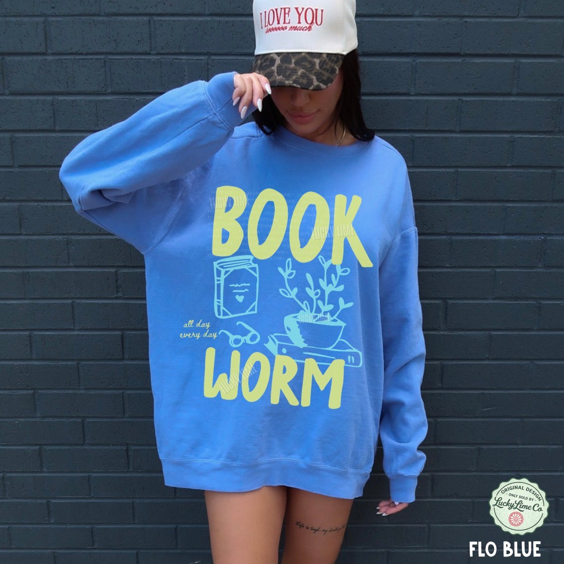 Person wearing a blue sweatshirt with 'BOOK WORM' text against a dark brick wall.