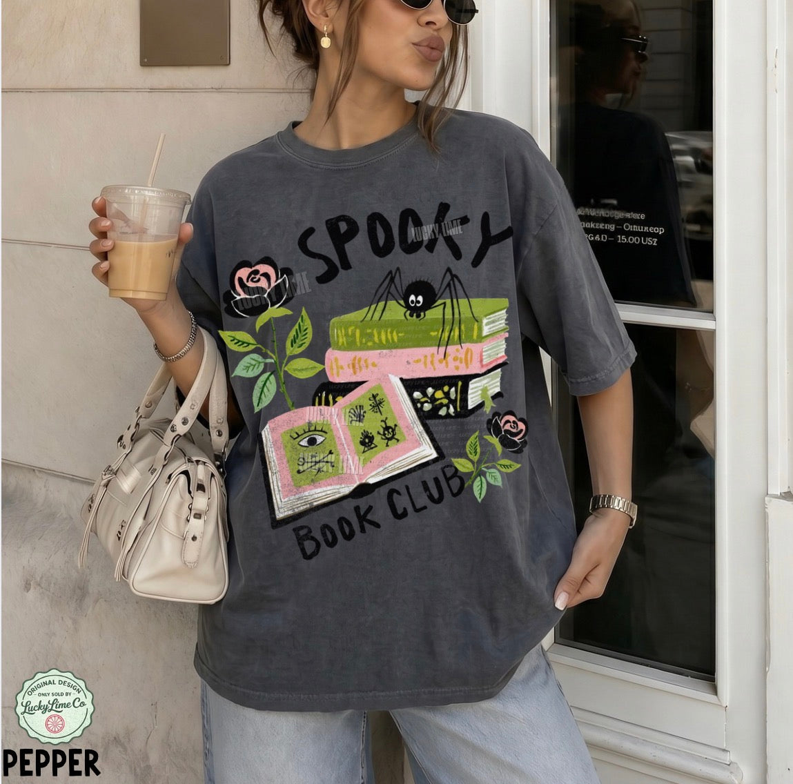Person wearing a 'Spooky Book Club' t-shirt holding a drink.