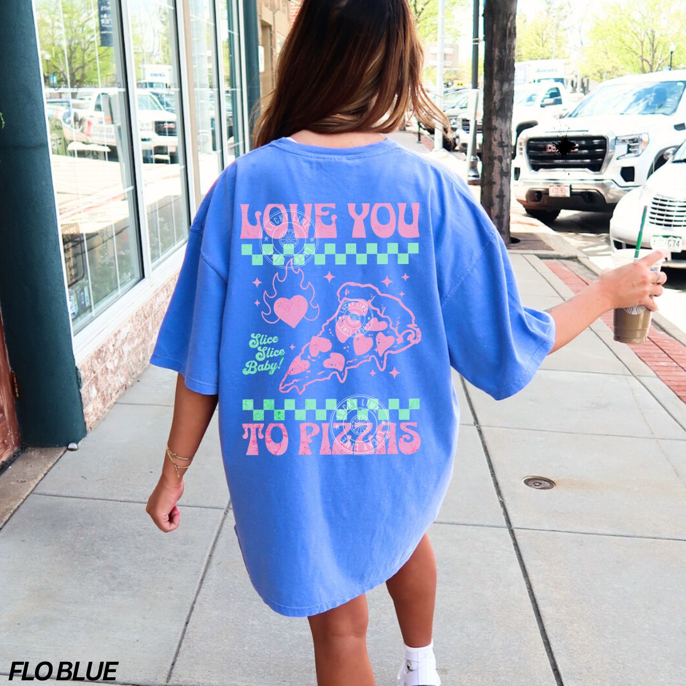 Person wearing a blue oversized t-shirt with colorful text and graphics, standing on a sidewalk.