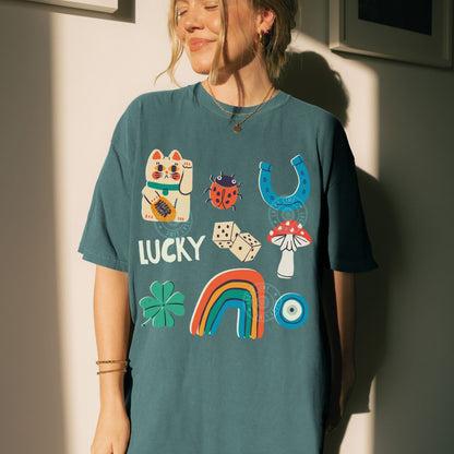 Person wearing a teal t-shirt with colorful lucky charms graphics and text, standing against a light-colored wall.