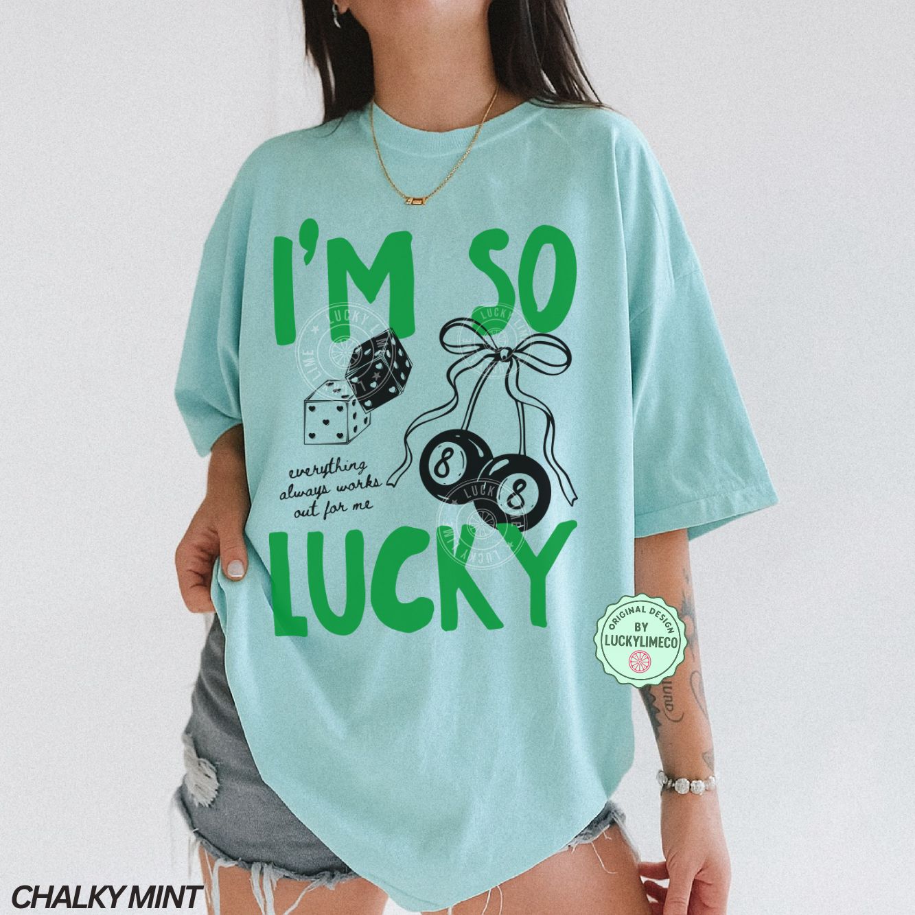 Person wearing a chalky mint t-shirt with 'I'm so lucky' text and graphics on a white background