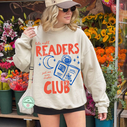 Person wearing a sand gildan sweatshirt with 'late night READERS CLUB' text in a flower shop