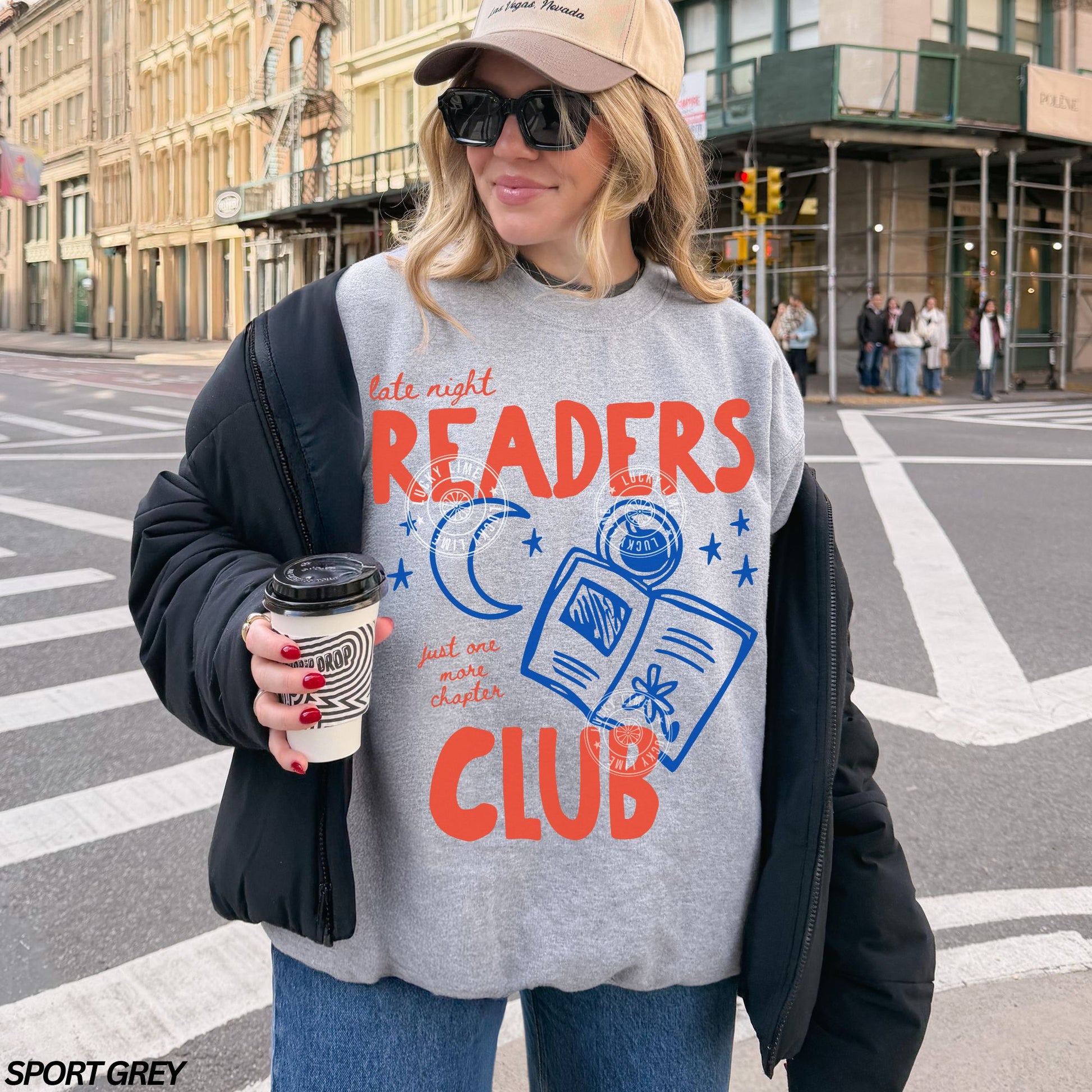Person wearing a 'Late Night Readers Club' sweatshirt on a city street.