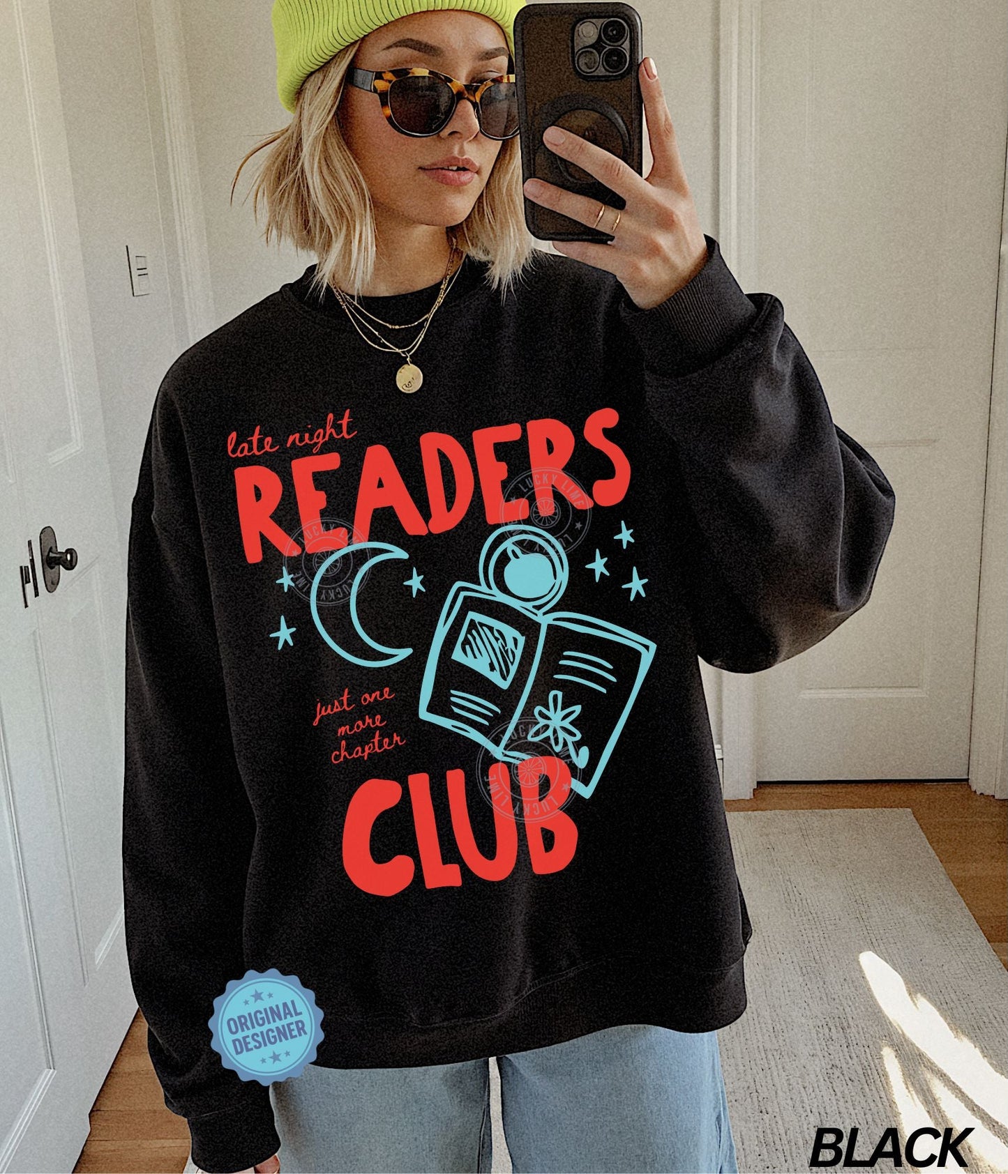 Person wearing a black sweatshirt with 'Late Night Readers Club' design, taking a mirror selfie.