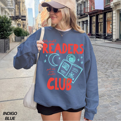 Person wearing a blue sweatshirt with 'late night Readers Club' text on a city street.