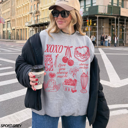 Person wearing a gray sweatshirt with red Valentine graphics and text, holding a coffee cup on a city street.