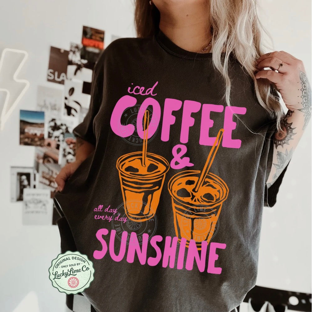 Person wearing a t-shirt with 'iced coffee & sunshine' text and graphics.