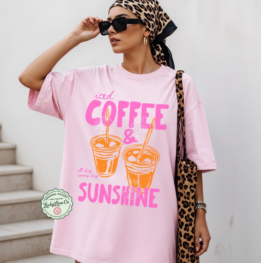 Woman wearing a pink t-shirt with coffee and sunshine design, holding sunglasses and a leopard print bag.