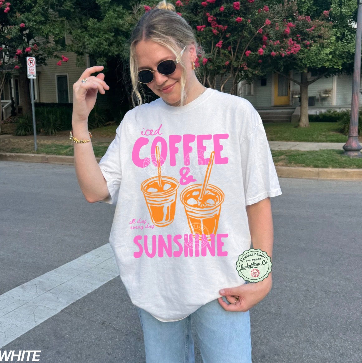 Person wearing a white t-shirt with 'iced coffee & sunshine' design outdoors.