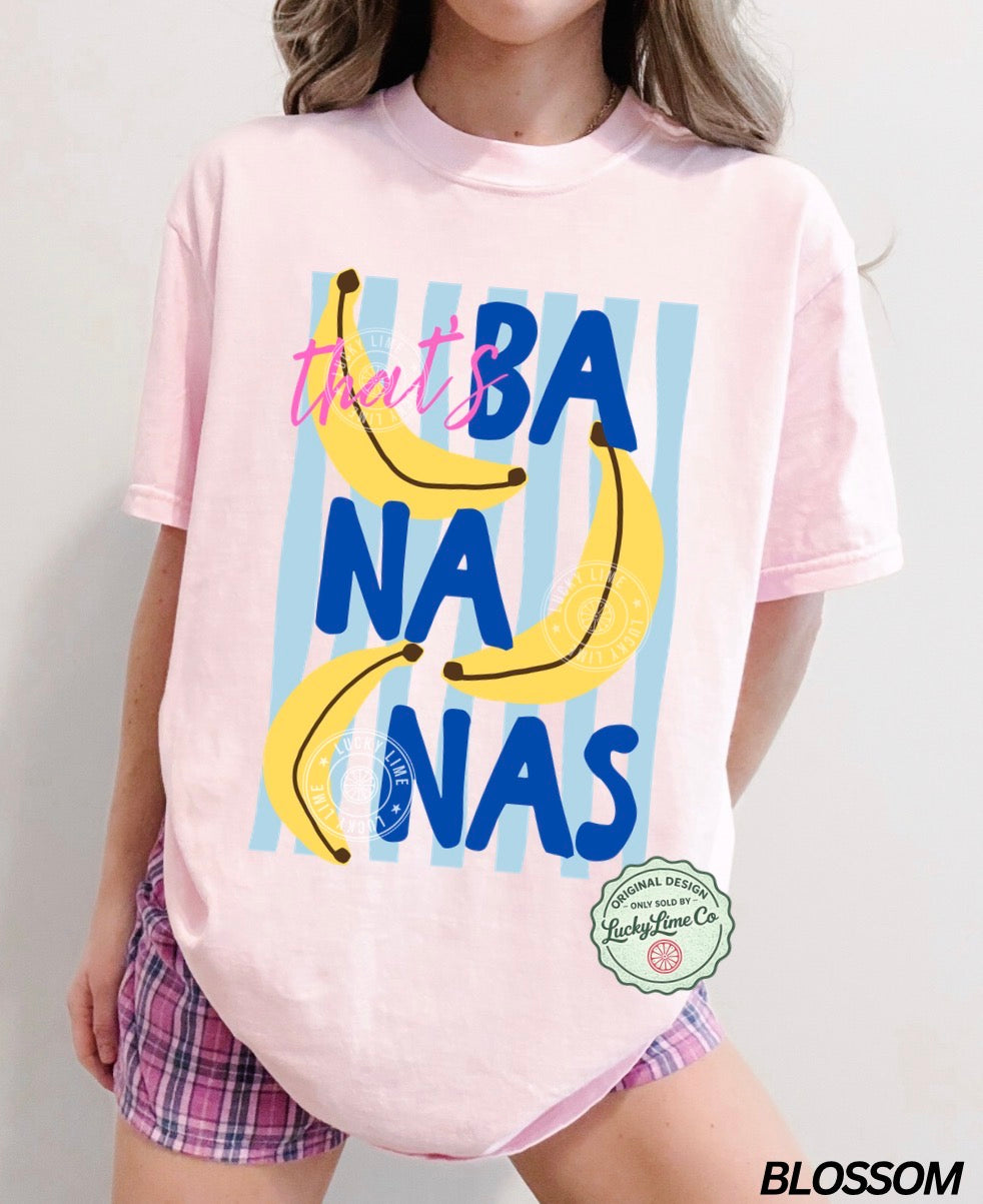 Person wearing a pink t-shirt with 'that's bananas' graphic and plaid shorts on a plain background