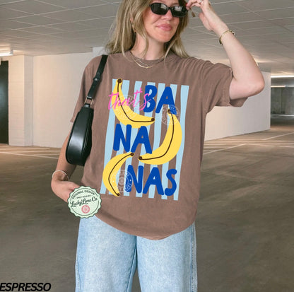 Person wearing a brown t-shirt with banana graphic and text in an indoor setting