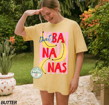 Person wearing a yellow t-shirt with 'that's bananas' text and banana graphics outdoors.