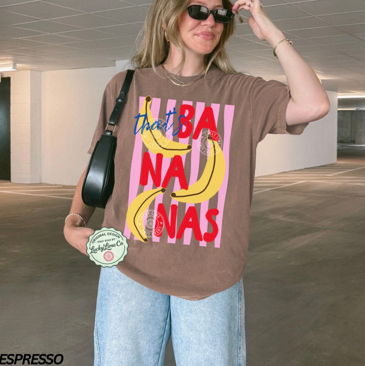 Person wearing a brown t-shirt with banana graphic and text in an indoor setting