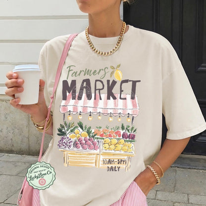 Person wearing a 'Farmers Market' t-shirt with graphics, holding a coffee cup.