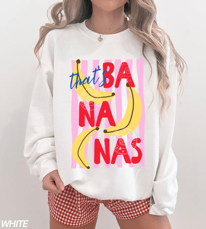 Person wearing a white sweatshirt with colorful banana graphic and text on a plain background