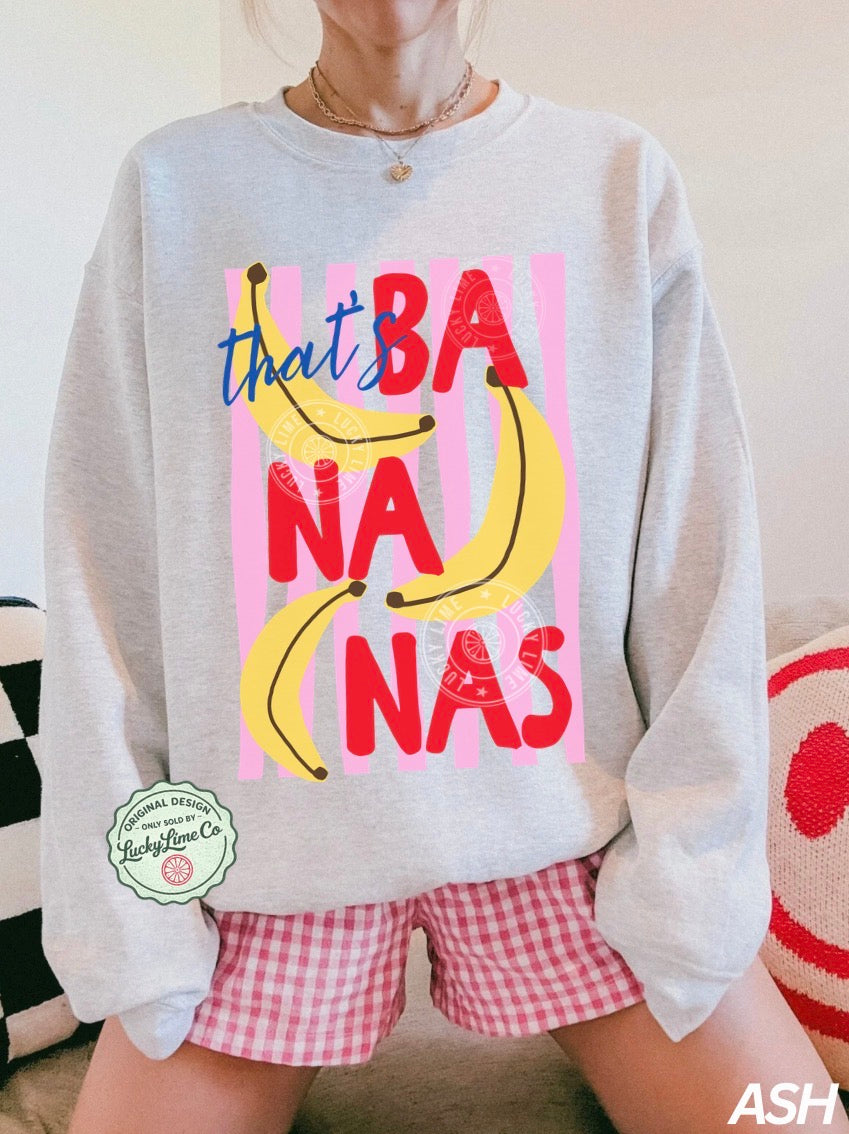 Person wearing a gray sweatshirt with colorful text and bananas, sitting on a couch.