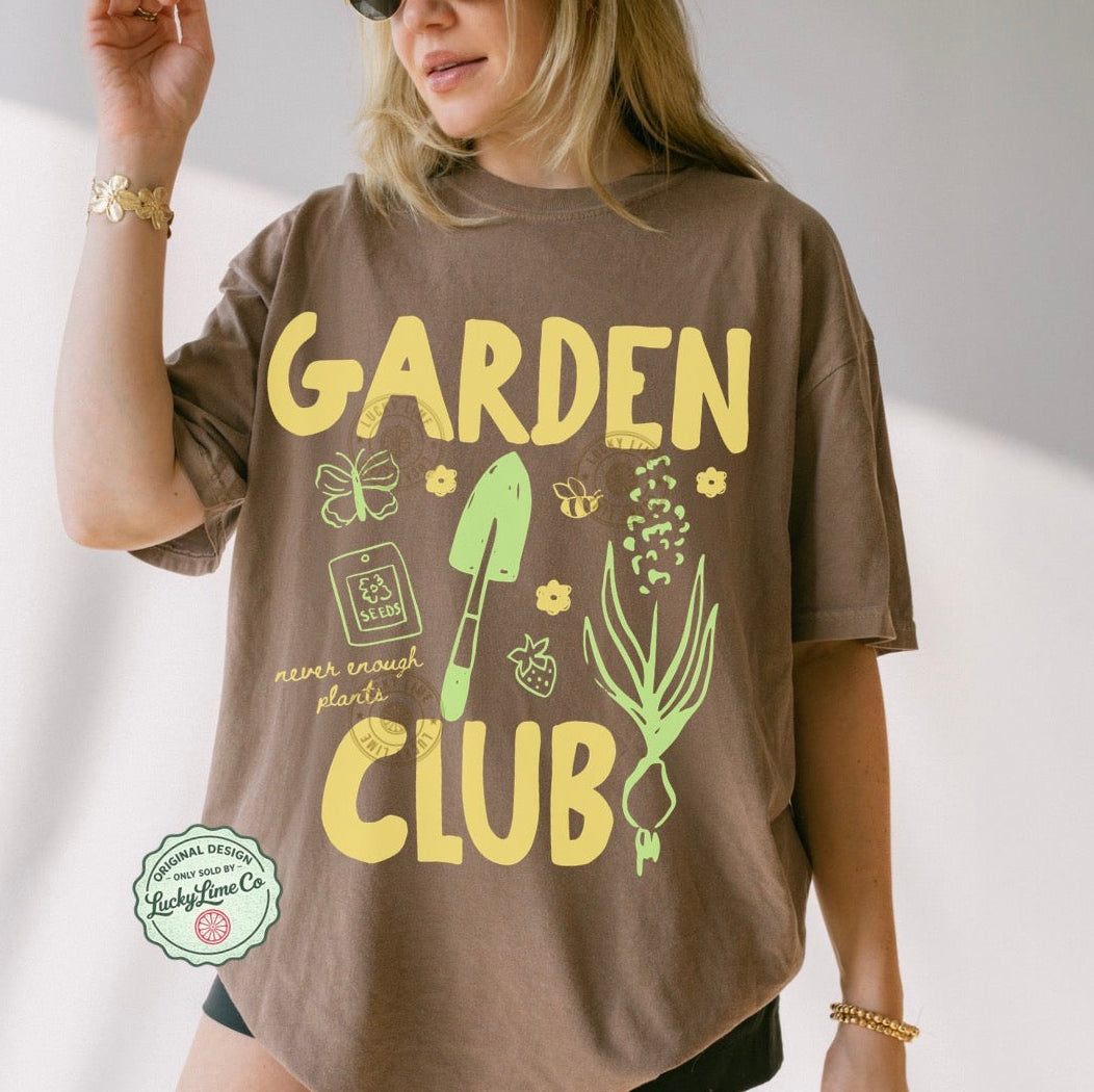 Person wearing a brown t-shirt with 'Garden Club' text and graphics on a plain background
