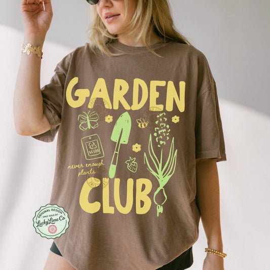 Person wearing a brown t-shirt with 'Garden Club' text and graphics on a plain background