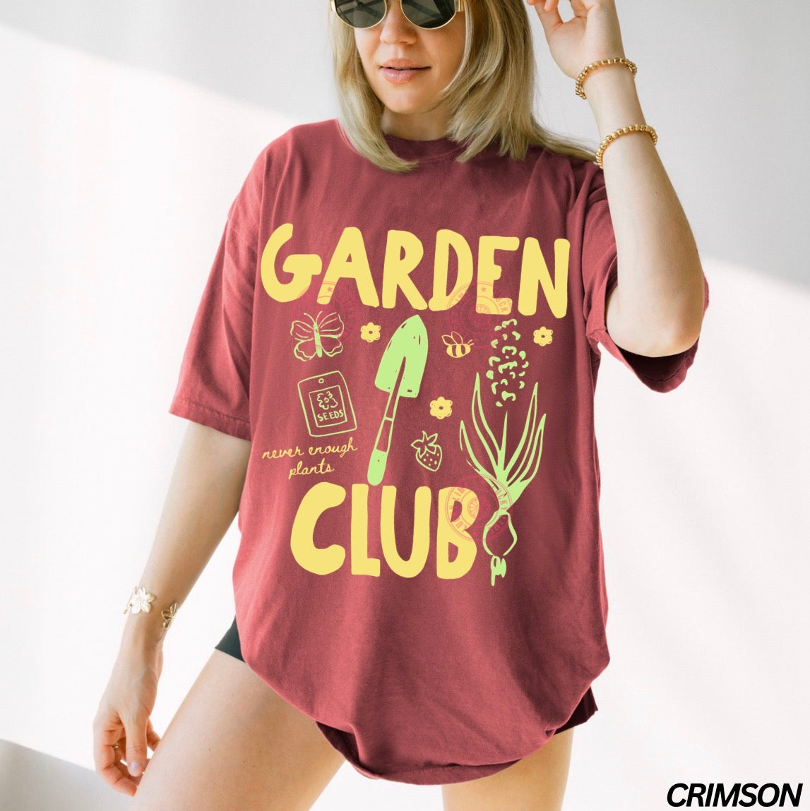 Person wearing a crimson t-shirt with 'Garden Club' text and graphics on a white background