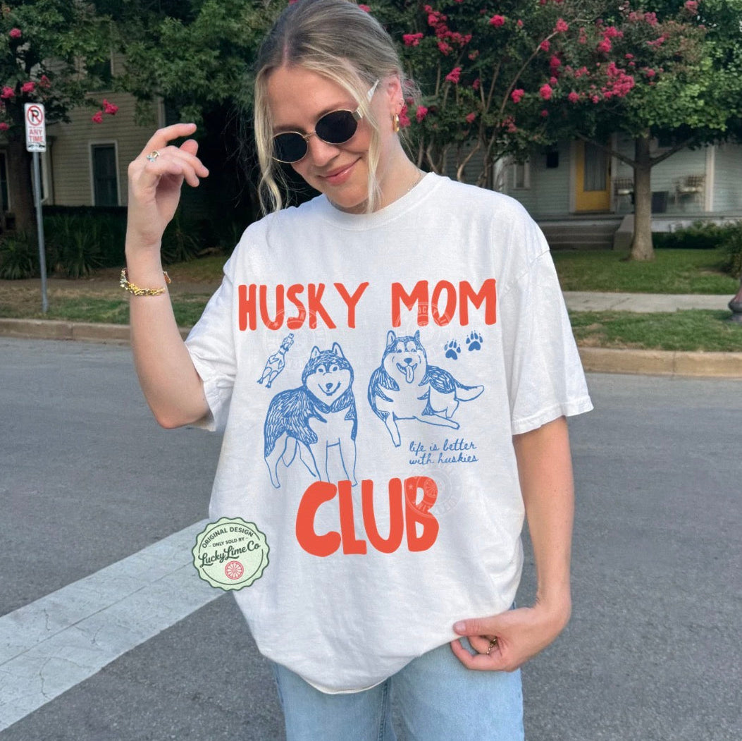 Person wearing a 'Husky Mom Club' t-shirt on a street.