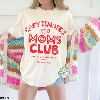 Person wearing a 'Caffeinated Moms Club' t-shirt with a colorful cardigan.