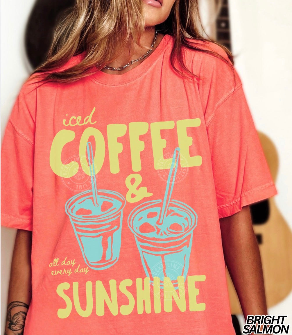 Person wearing a coral t-shirt with 'iced coffee & sunshine' text and graphics.