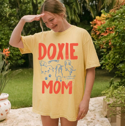 Woman wearing a yellow 'Doxie Mom' t-shirt outdoors.