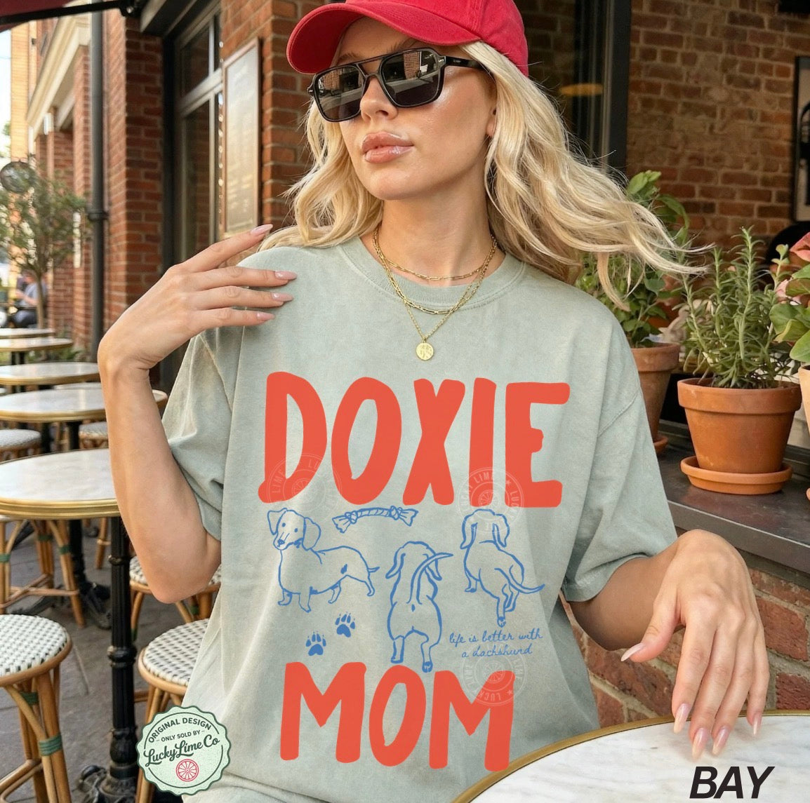 Woman wearing a 'Doxie Mom' t-shirt outdoors.