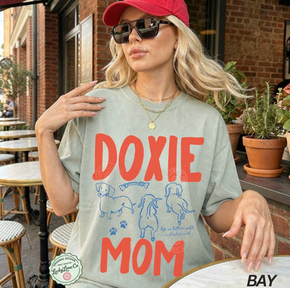Woman wearing a 'Doxie Mom' t-shirt outdoors.