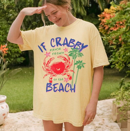 Person wearing a yellow t-shirt with a beach-themed design outdoors.