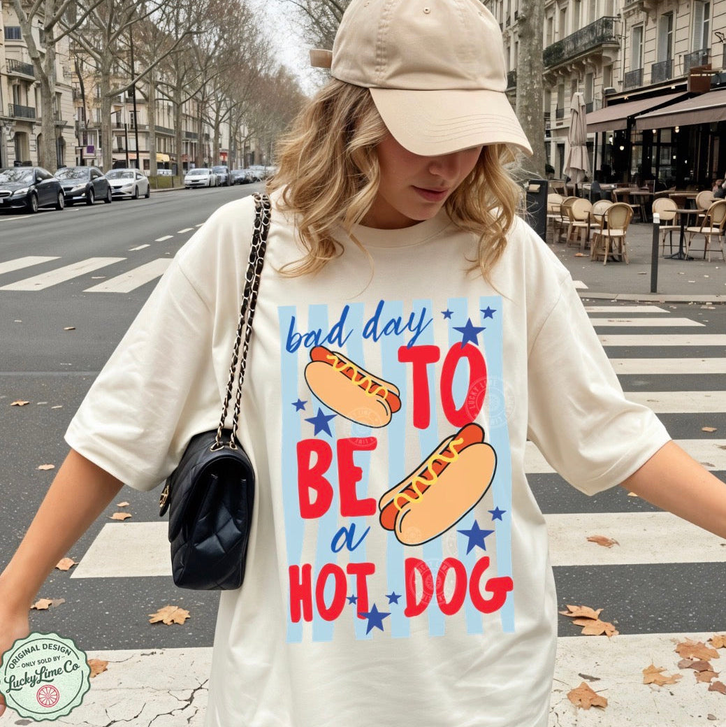 Person wearing a t-shirt with a hot dog graphic and text on a city street.