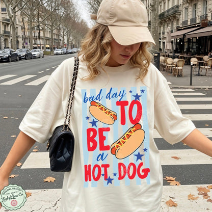 Person wearing a t-shirt with a hot dog graphic and text on a city street.