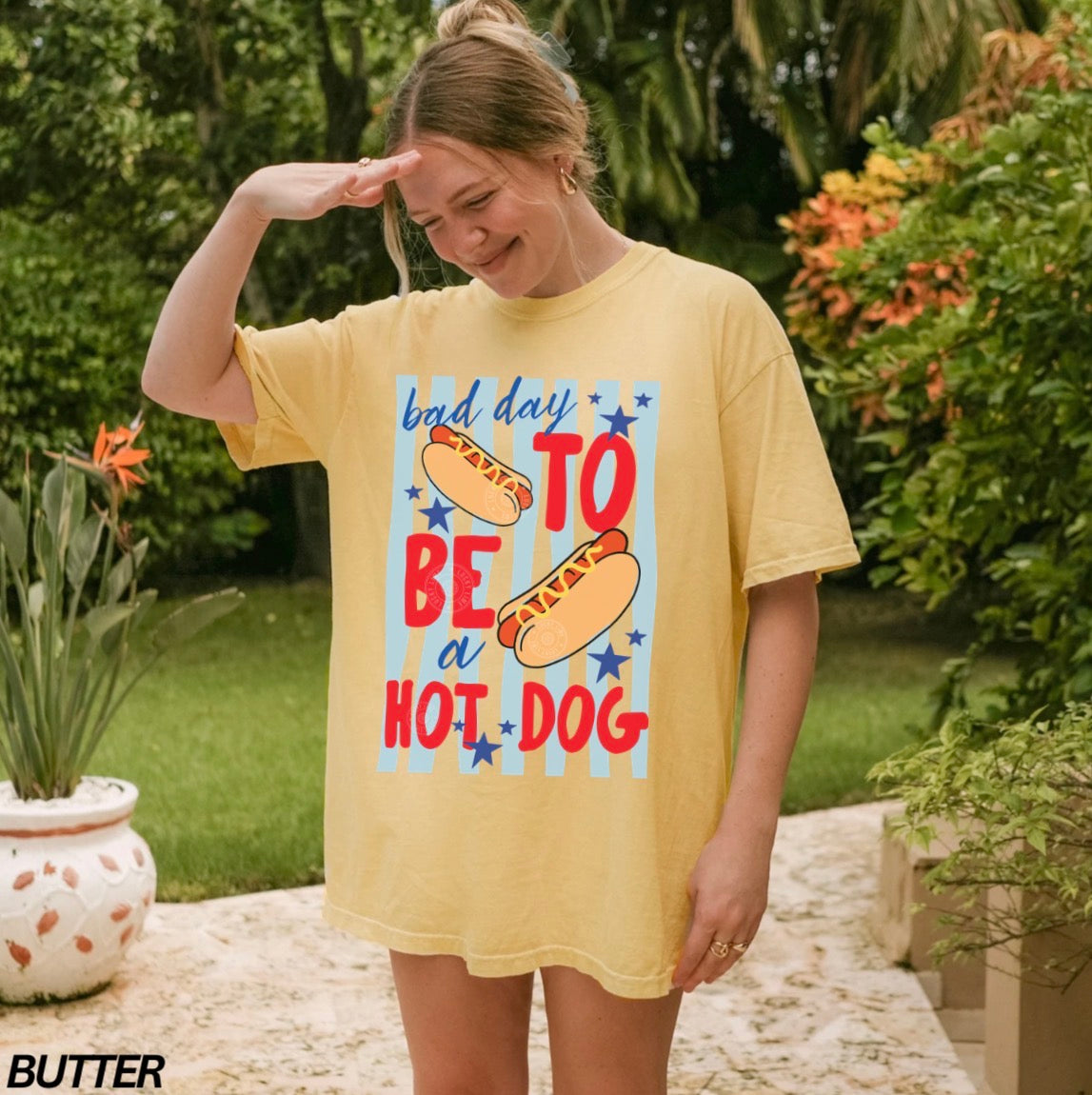 Woman wearing a yellow t-shirt with a hot dog graphic and text in an outdoor setting
