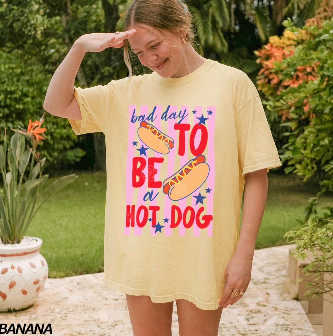 Person wearing a yellow t-shirt with a colorful graphic and text in an outdoor setting.
