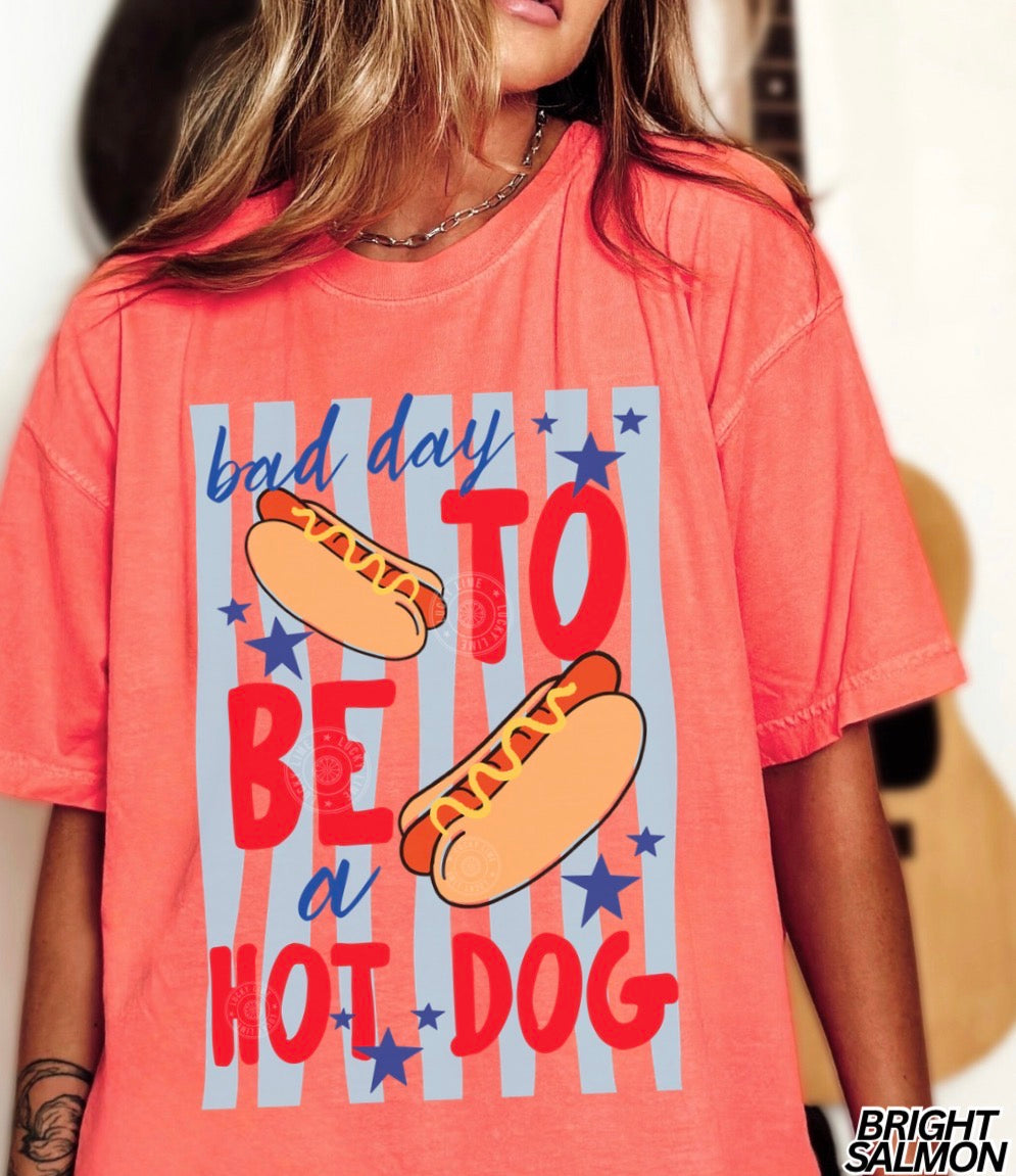 Person wearing a coral t-shirt with hot dog graphic and text